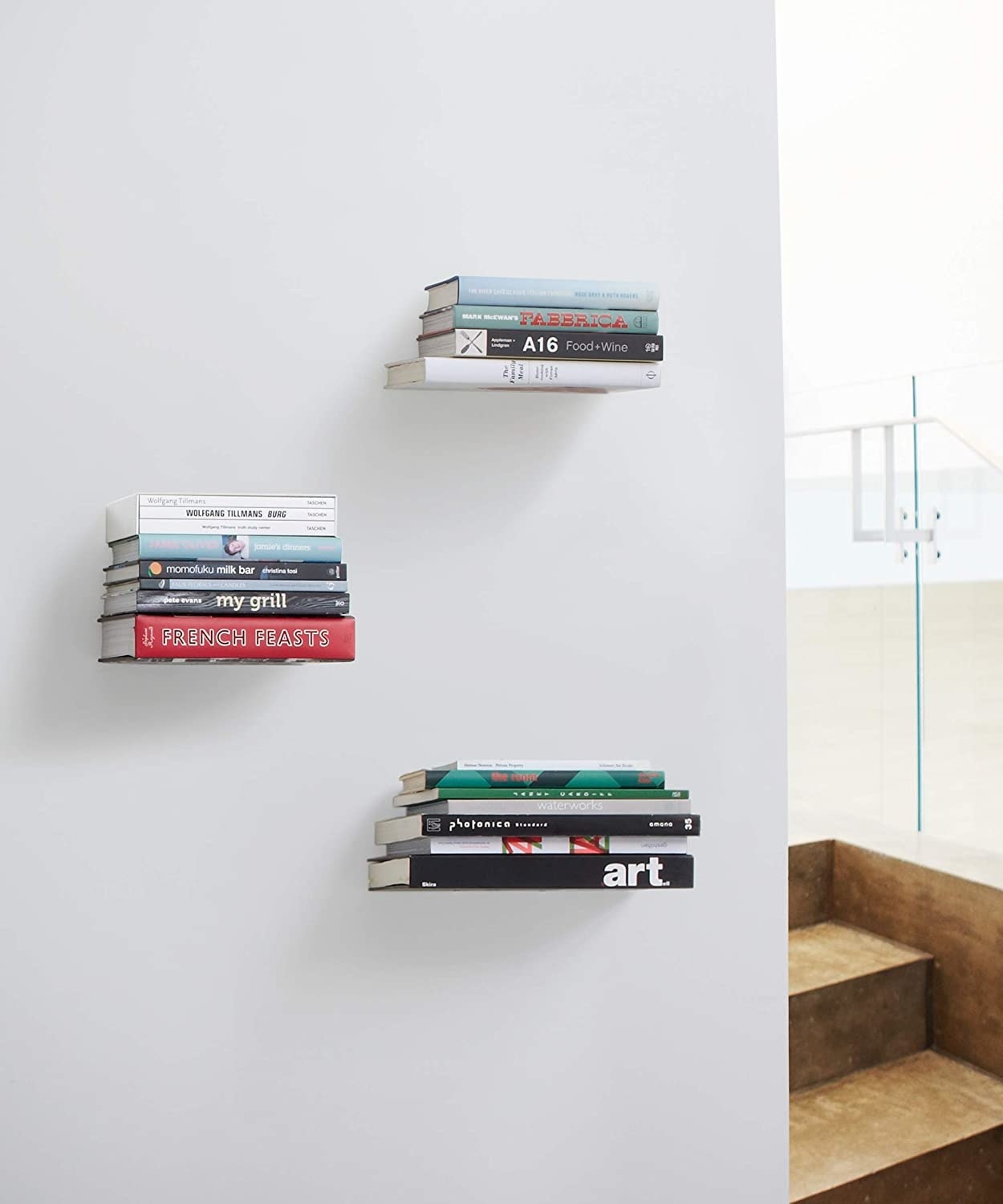 three floating bookshelves on a wall with books on them