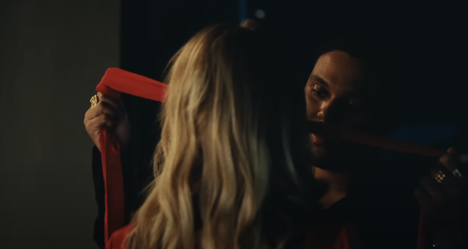 The Weeknd&#x27;s character holds a blindfold up to a female character