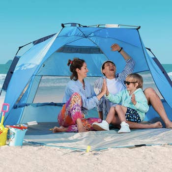 Family of three in the tent on a beach