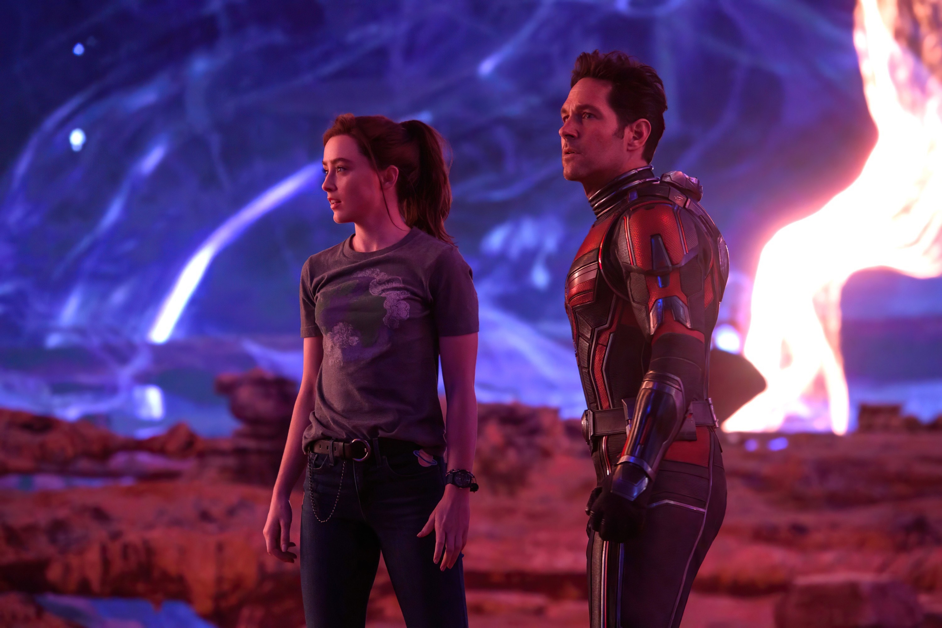 Ant-Man and his daughter stand in front of a purple sky and rocky background