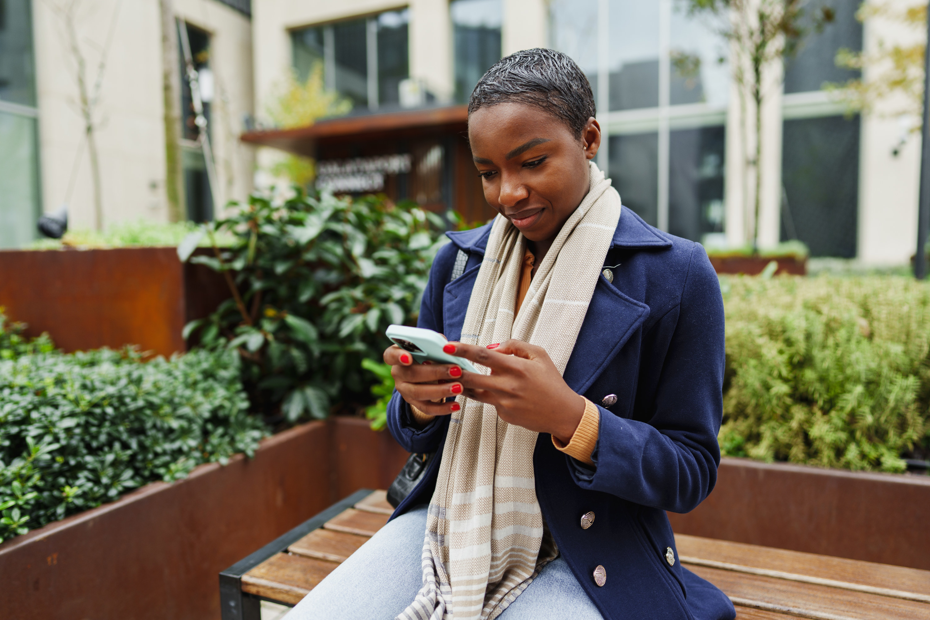 black woman using her phone in a courtyard