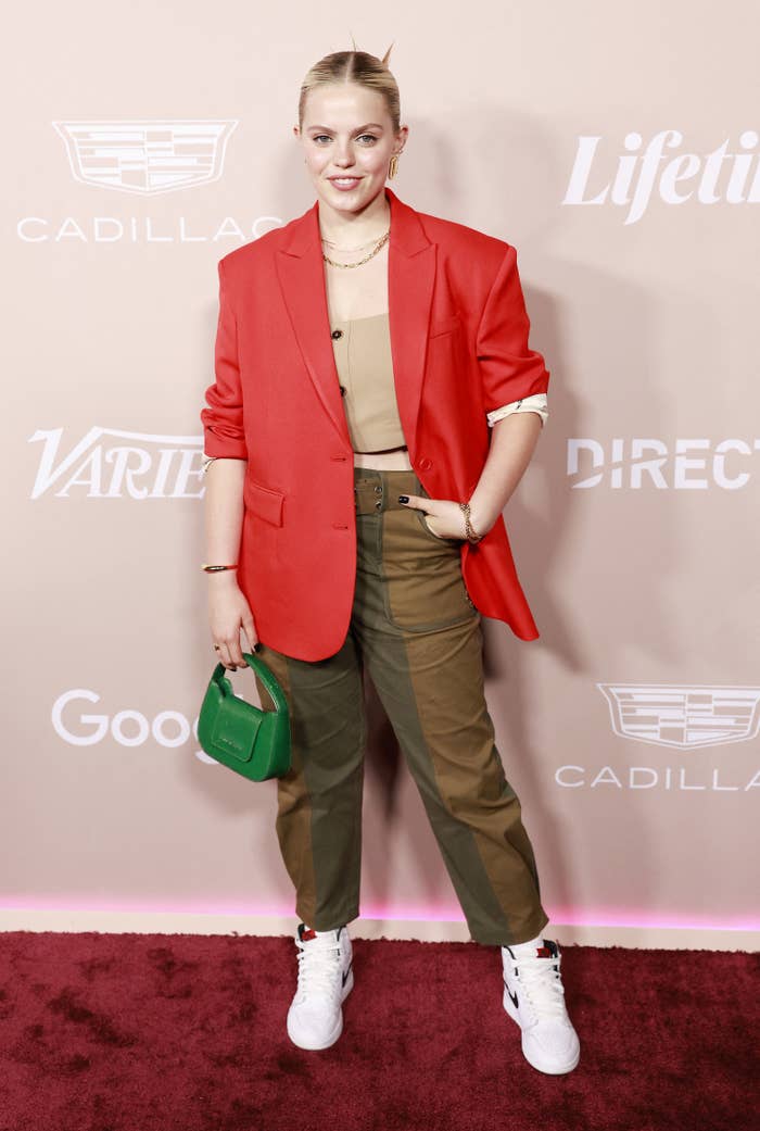 Reneé poses at a red carpet event wearing ankle-length pants, a crop top, a blazer, and Nike's