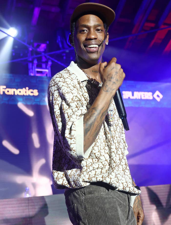 Travis holding mic and smiling as he stands onstage