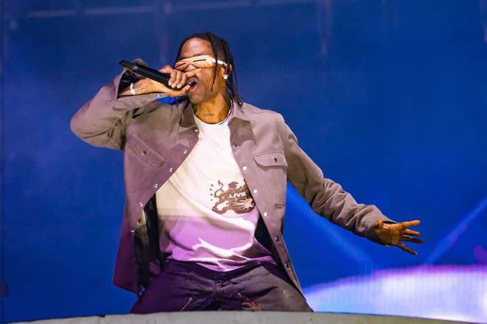 Travis performing onstage while wearing sunglasses; he's wearing a T-shirt, jacket, and jeans