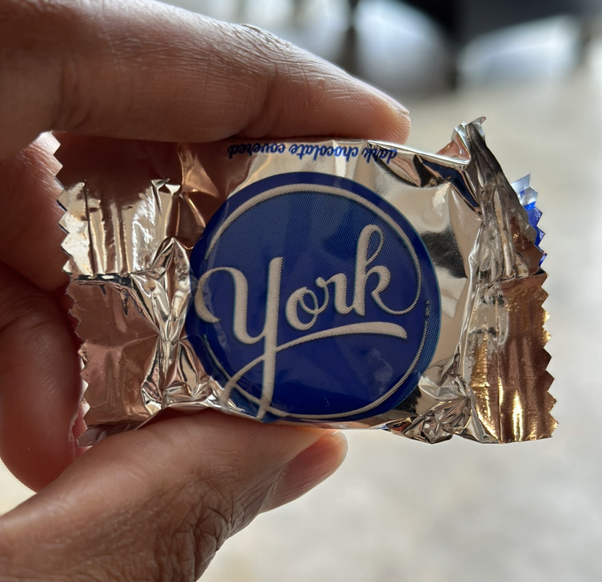 A hand holding a small packet of York Peppermint Patties