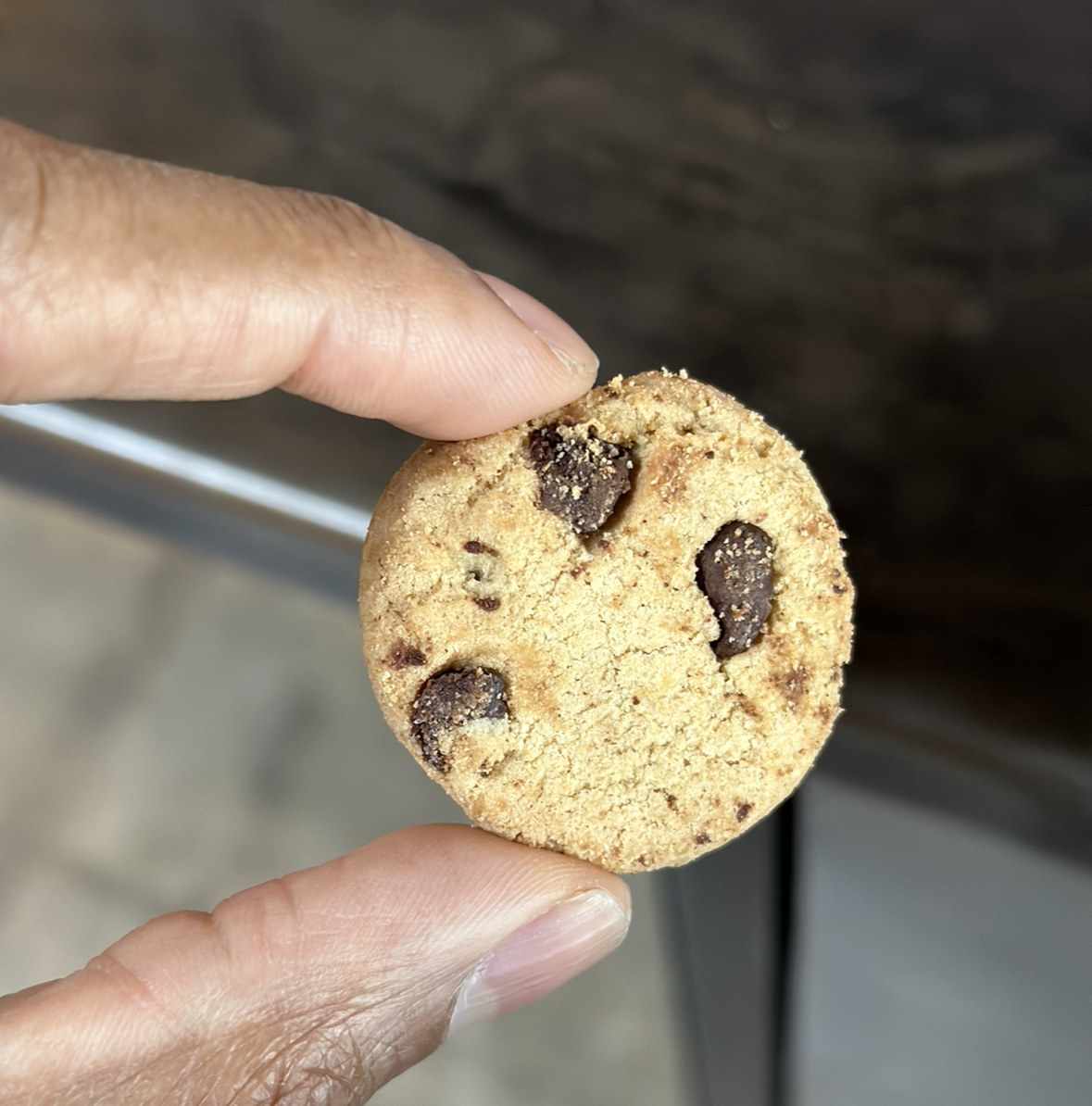A hand holding one Famous Amos bite-size cookie