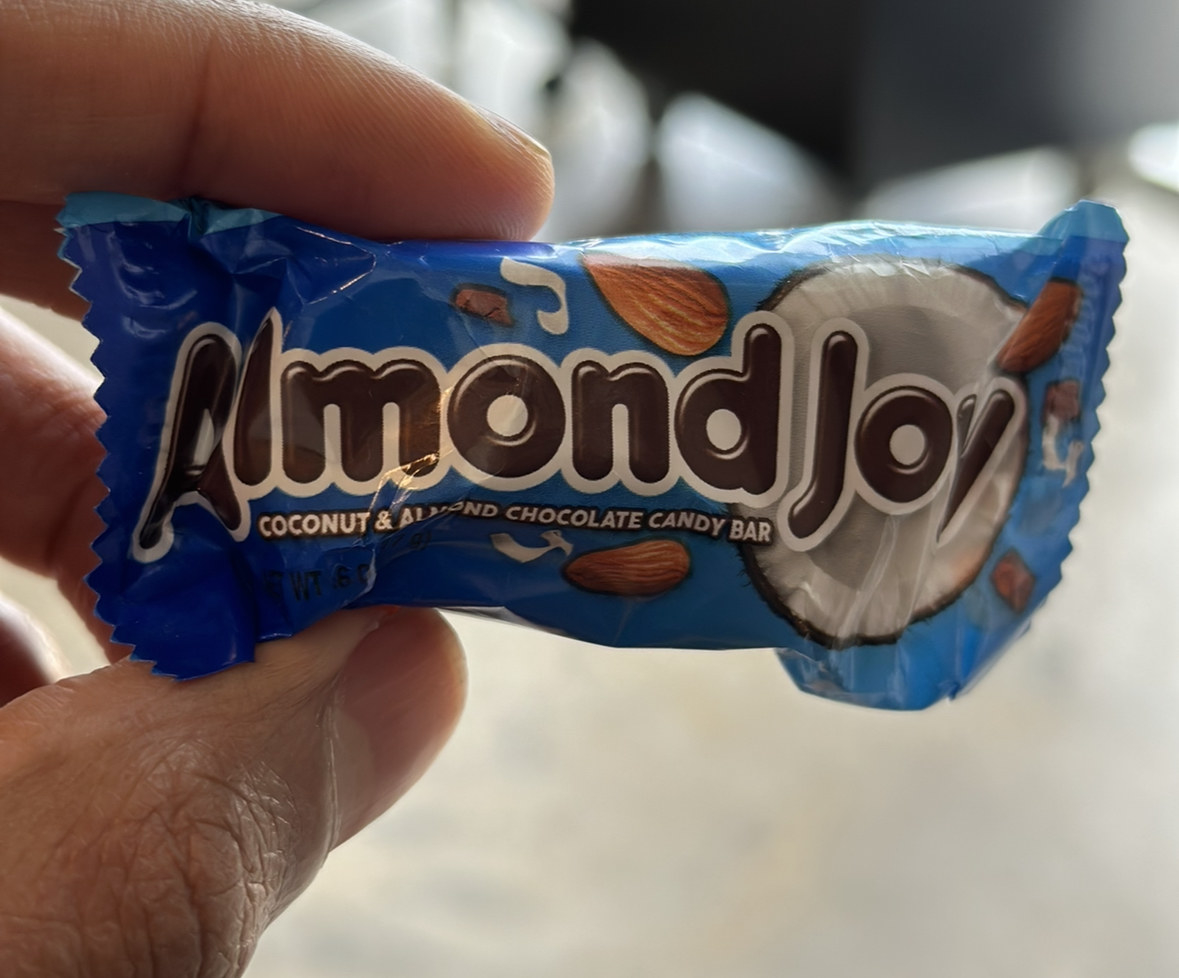 A hand holding a small bag of Almond Joy Coconut &amp;amp; Almond Chocolate Candy Bar