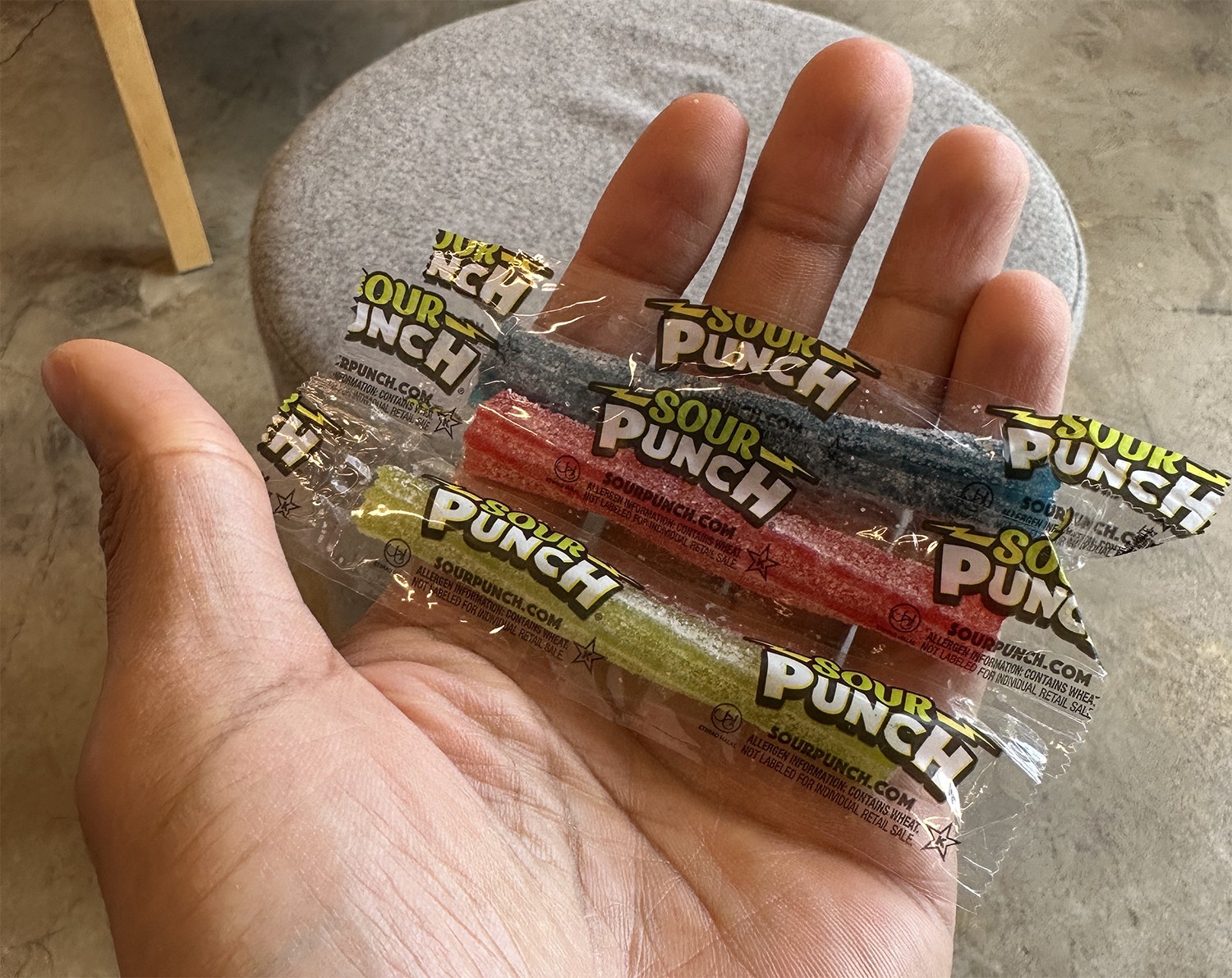 A hand holding a packet of Sour Punch Straws