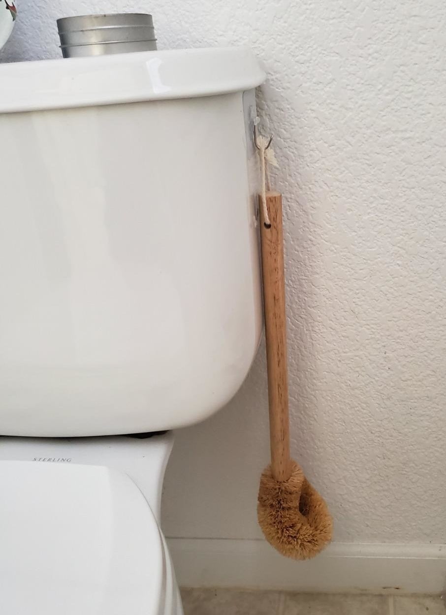 Brush hanging on the side of a toliet
