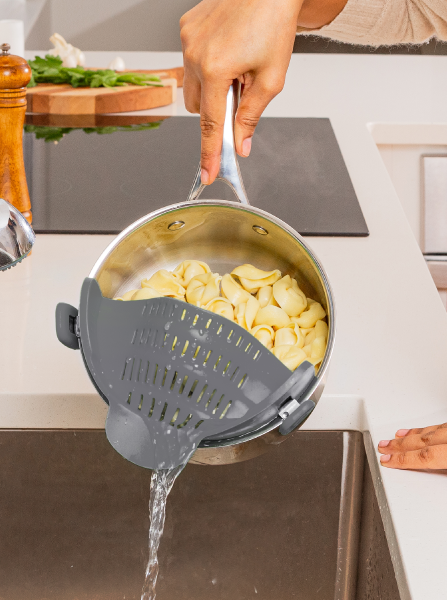 The strainer attached to a pot, which allows the water to drain while keeping pasta in place