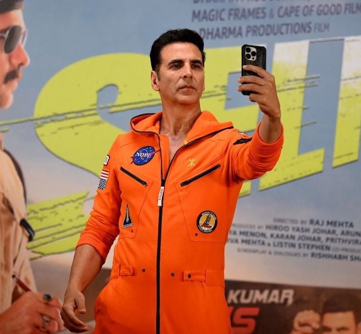Bollywood actor Akshay Kumar uses a mobile phone to take a selfie