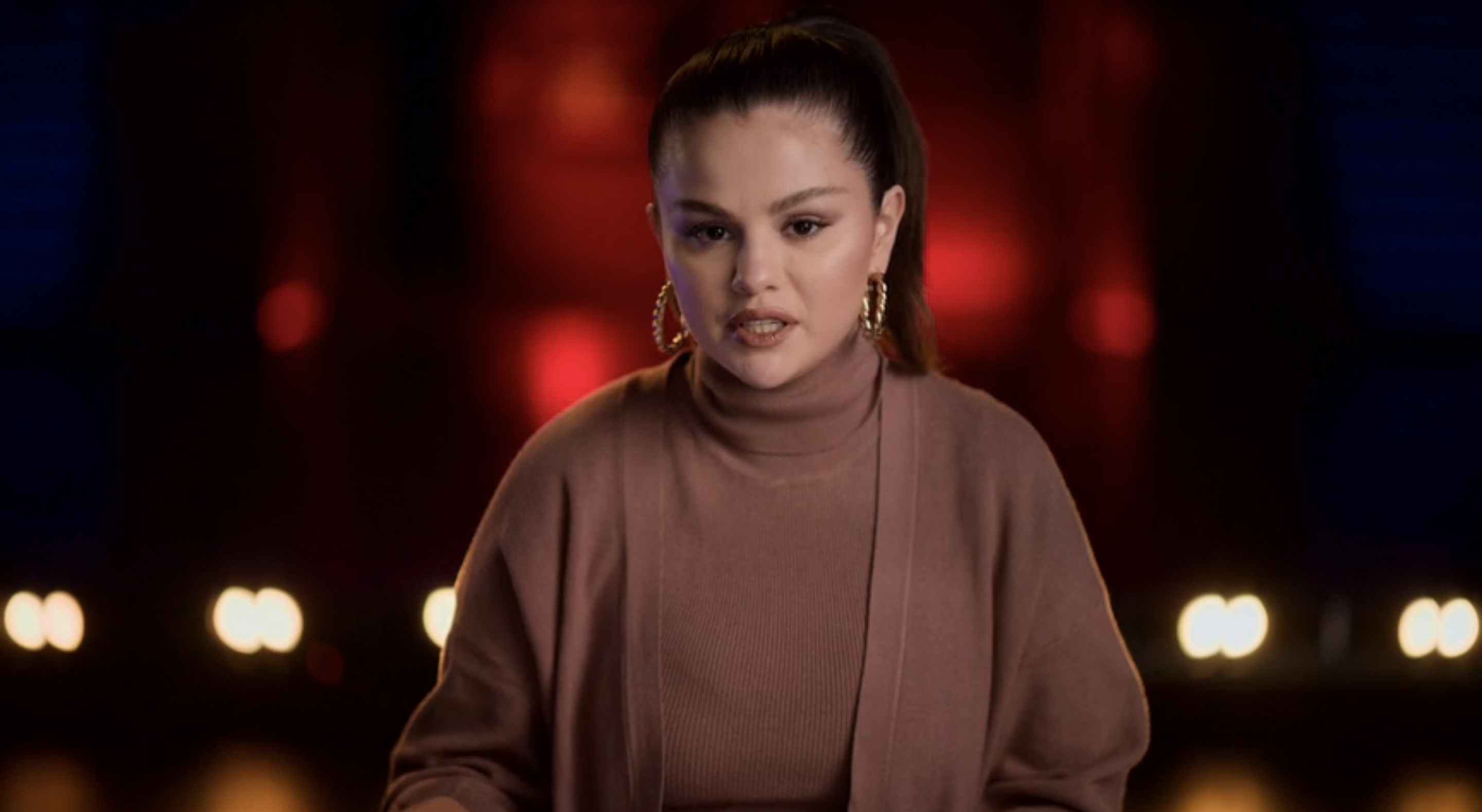 Close-up of Selena in a cardigan and turtleneck