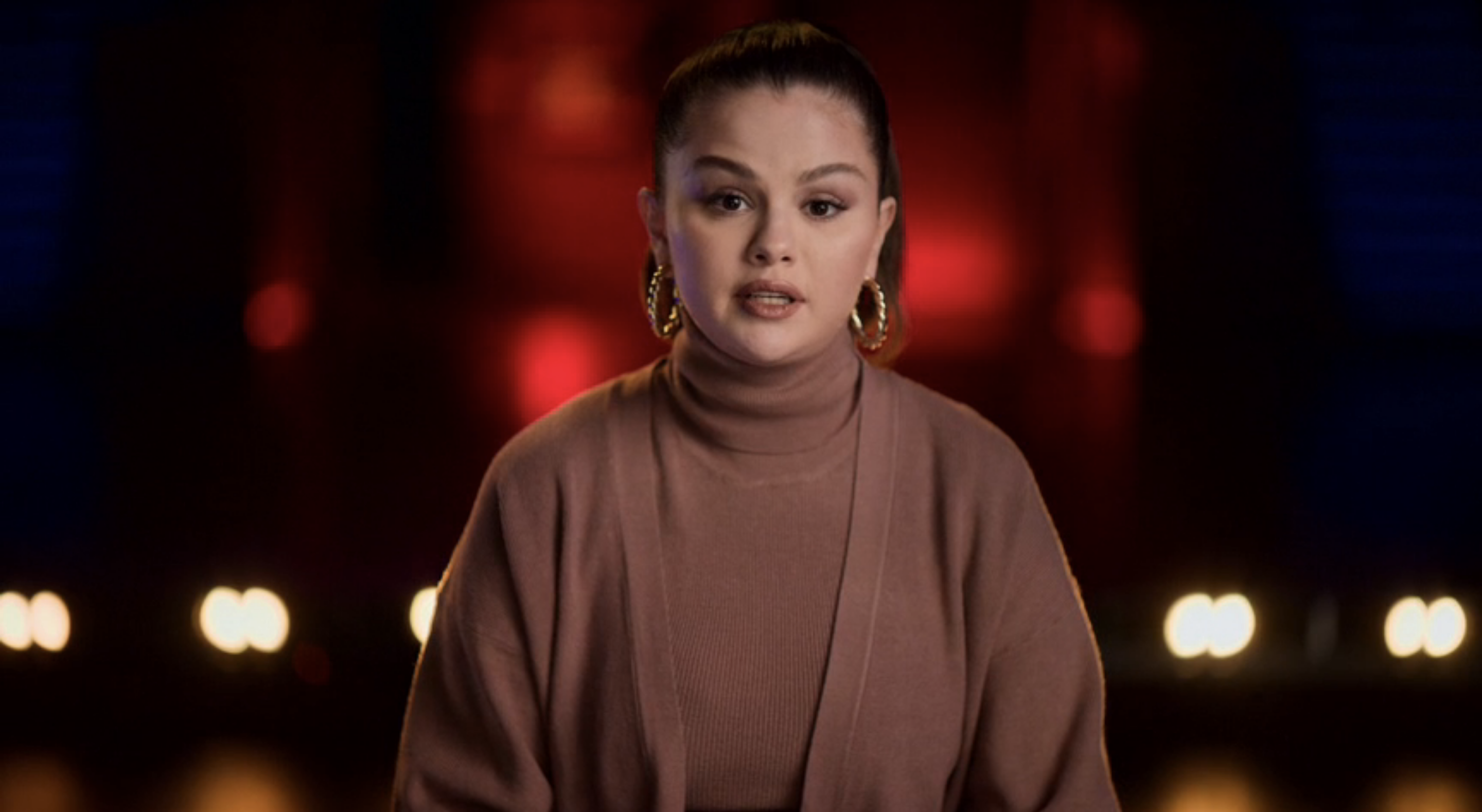 Close-up of Selena in a turtleneck and cardigan