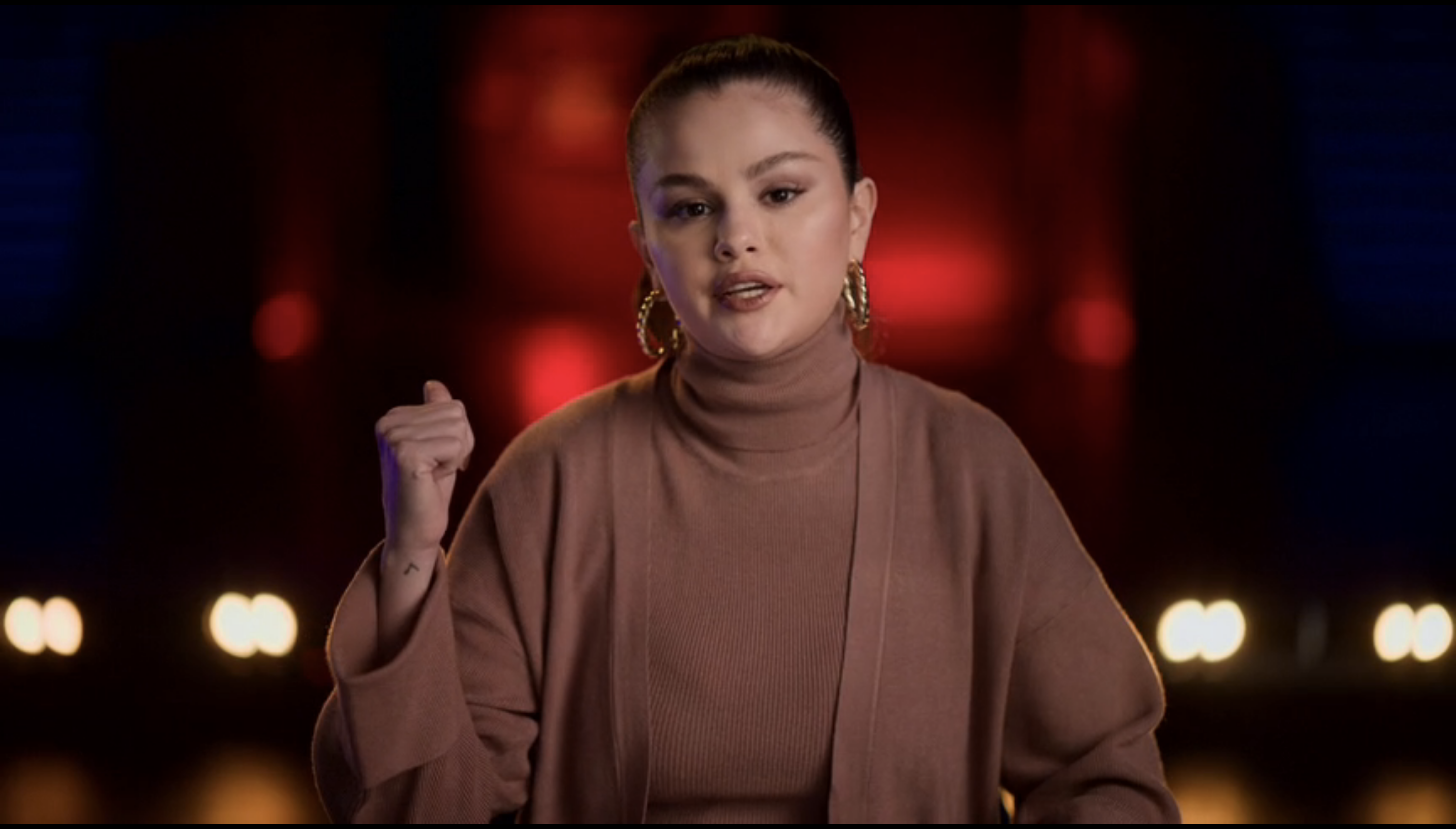 Close-up of Selena in a cardigan and turtleneck
