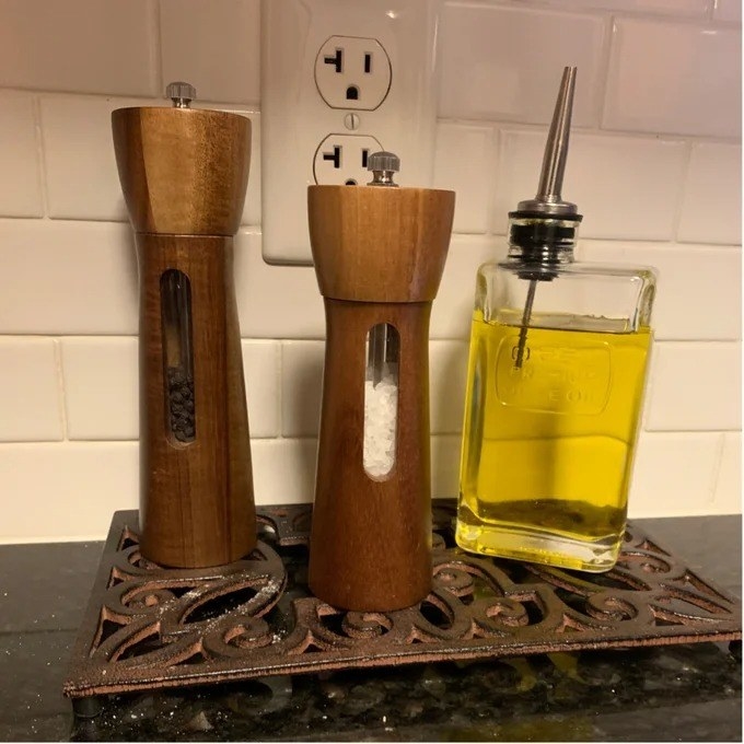 The salt and pepper grinder set next to a bottle of oil