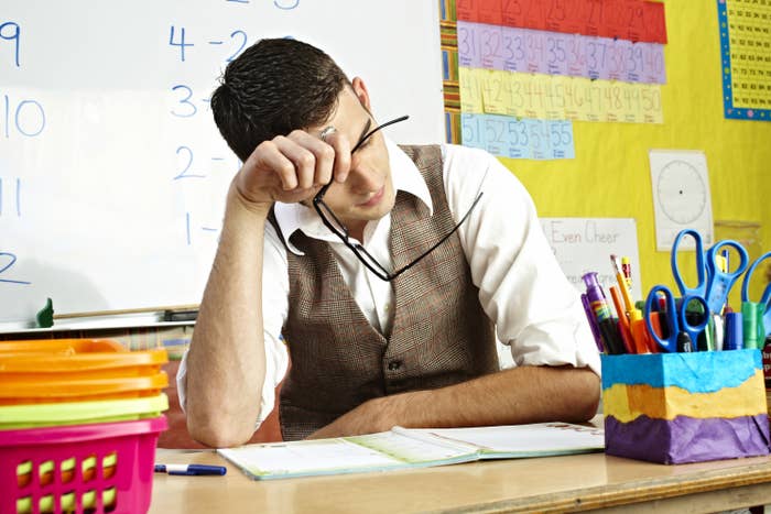 A male teacher is tired while reviewing paperwork