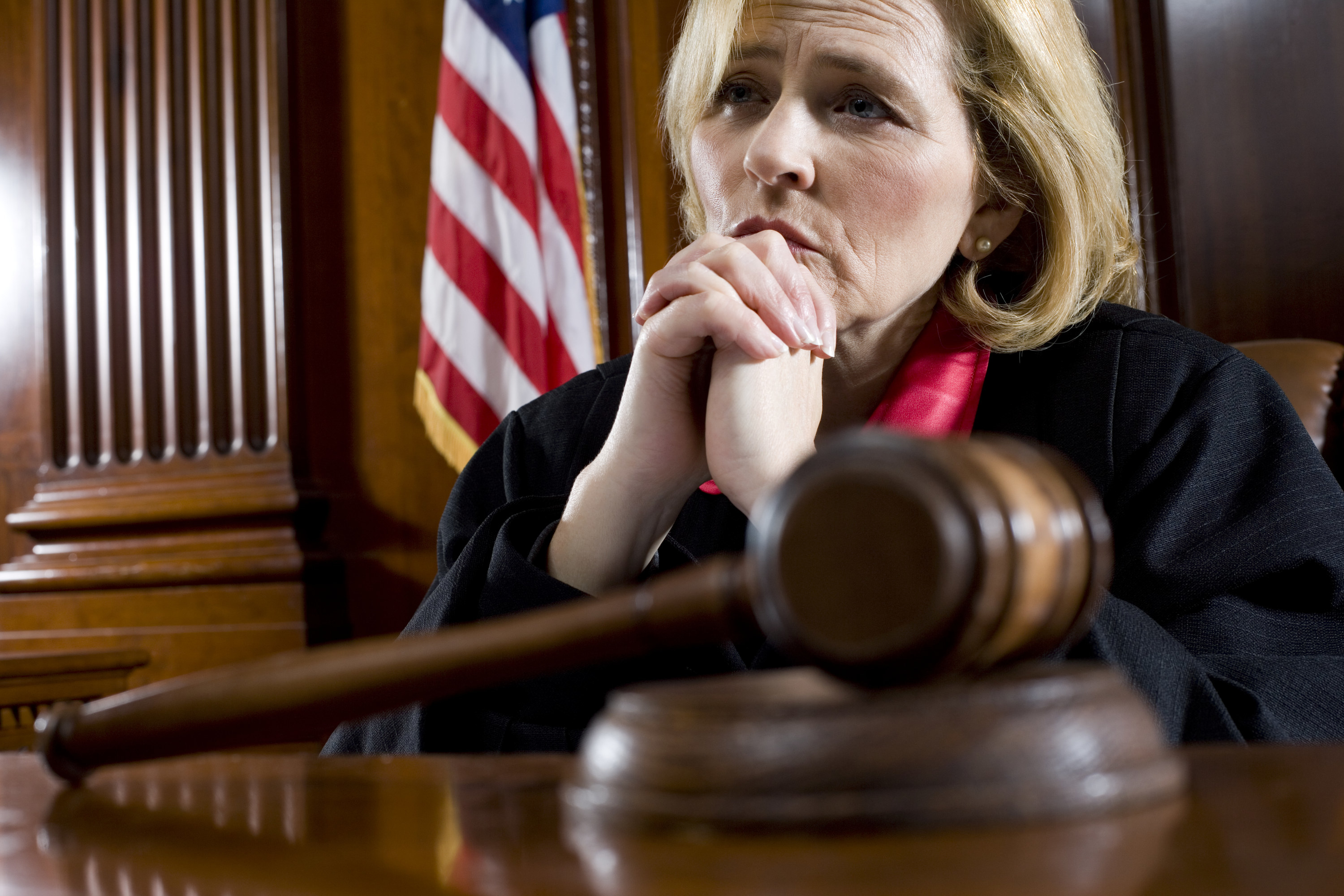 A female judge sits by her gavel and listens to people in a court room