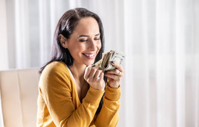 Satisfied smiling woman counting saved dollar bills