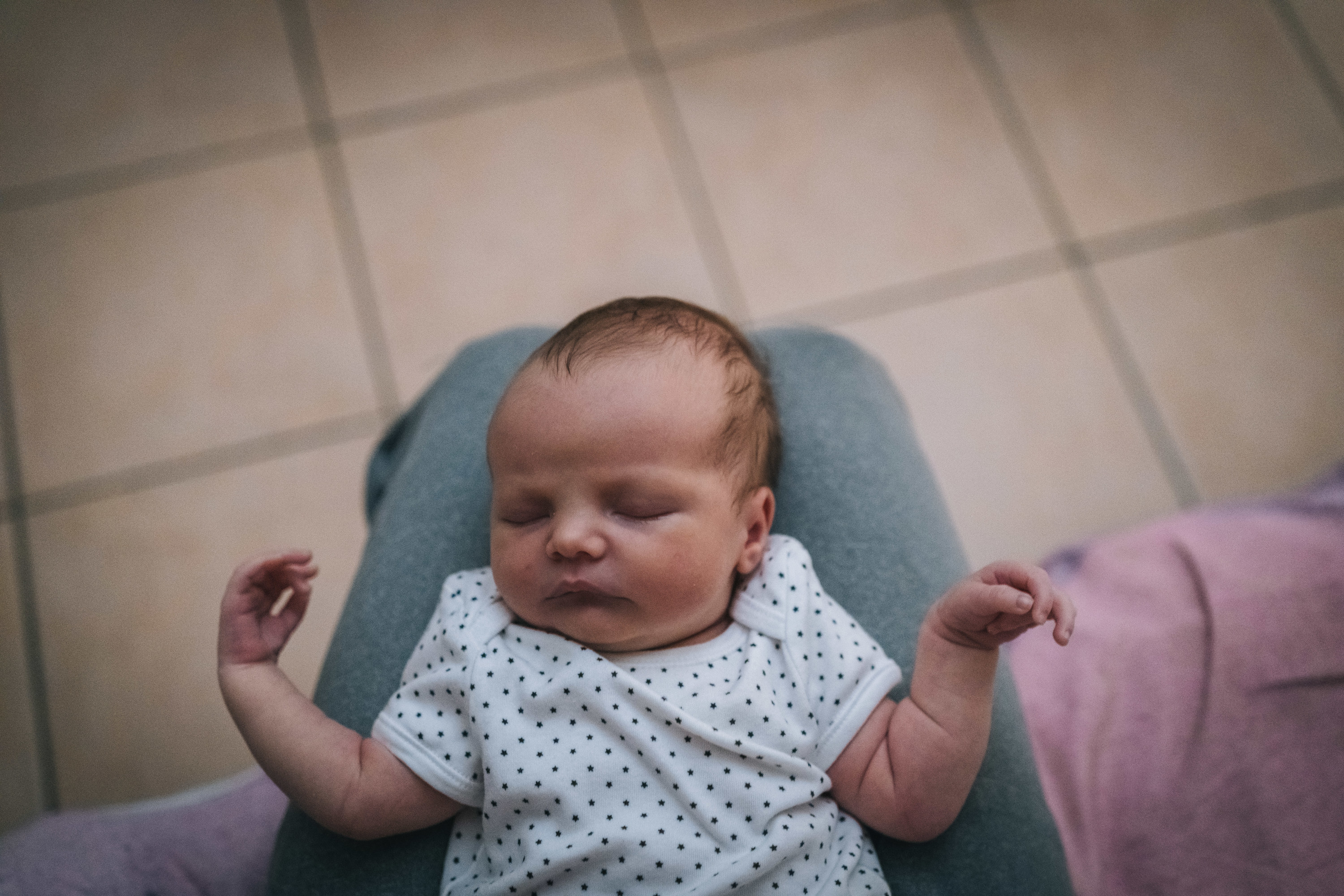 Baby sleeping on parent&#x27;s lap in onesie