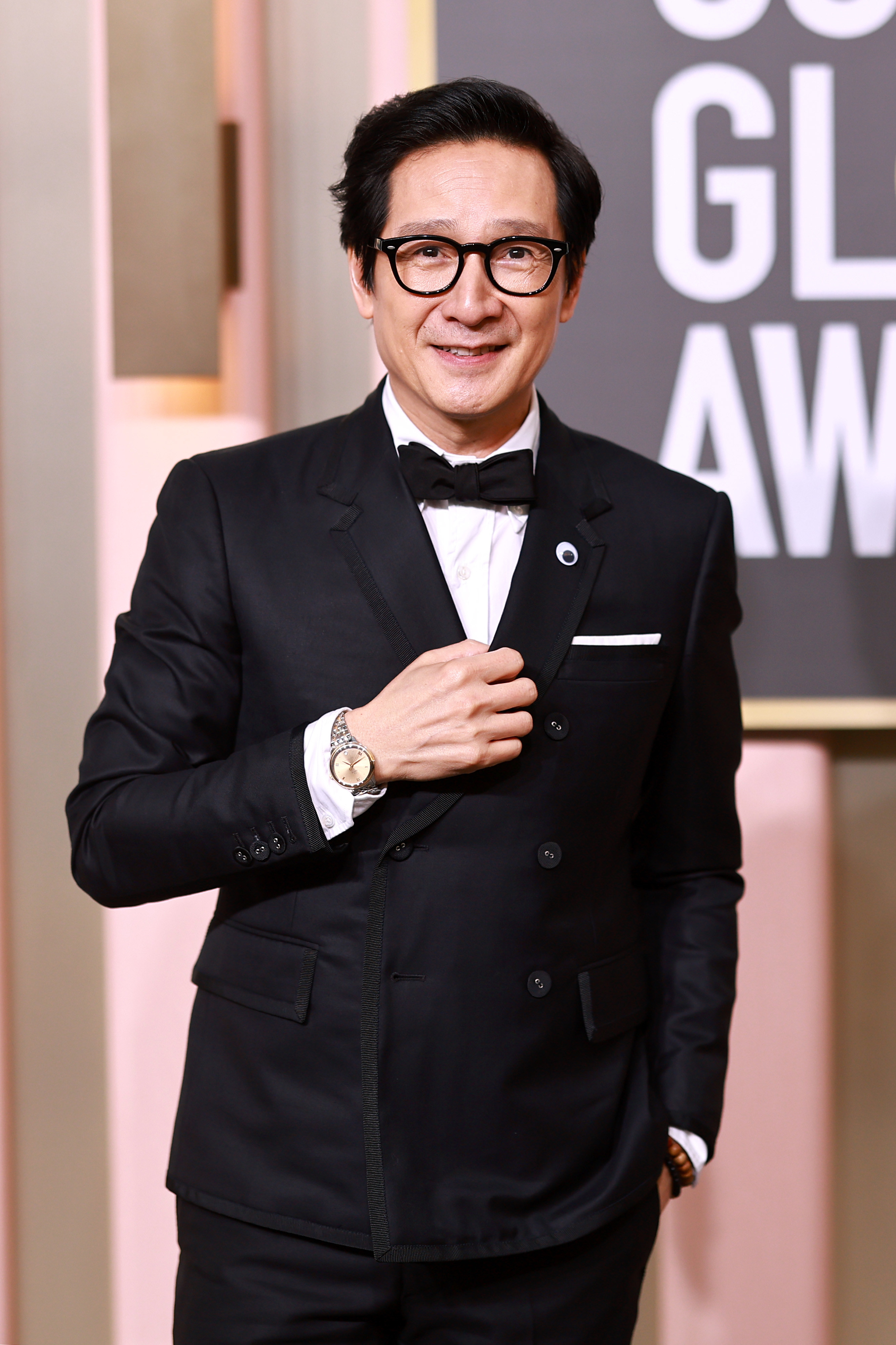 Ke Huy Quan smiles as his photo is taken at an awards show. He&#x27;s wearing a suit and bowtie