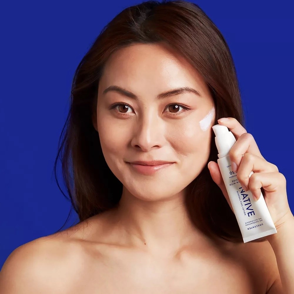 a model holding the tube of moisturizer and applying some to their face