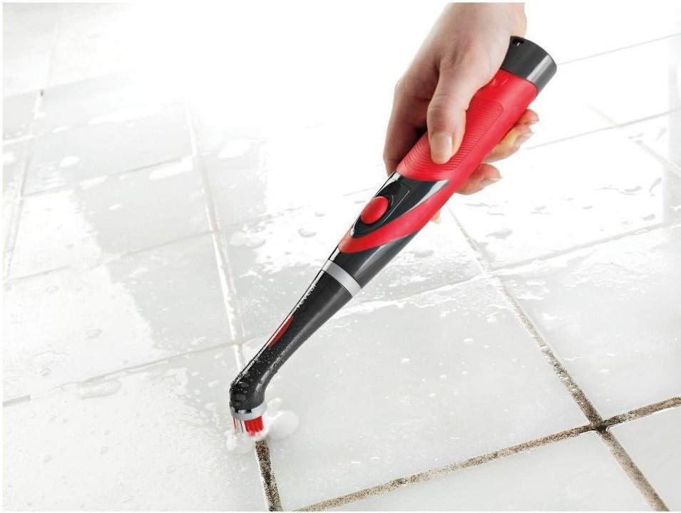 Model using the scrubber on grout