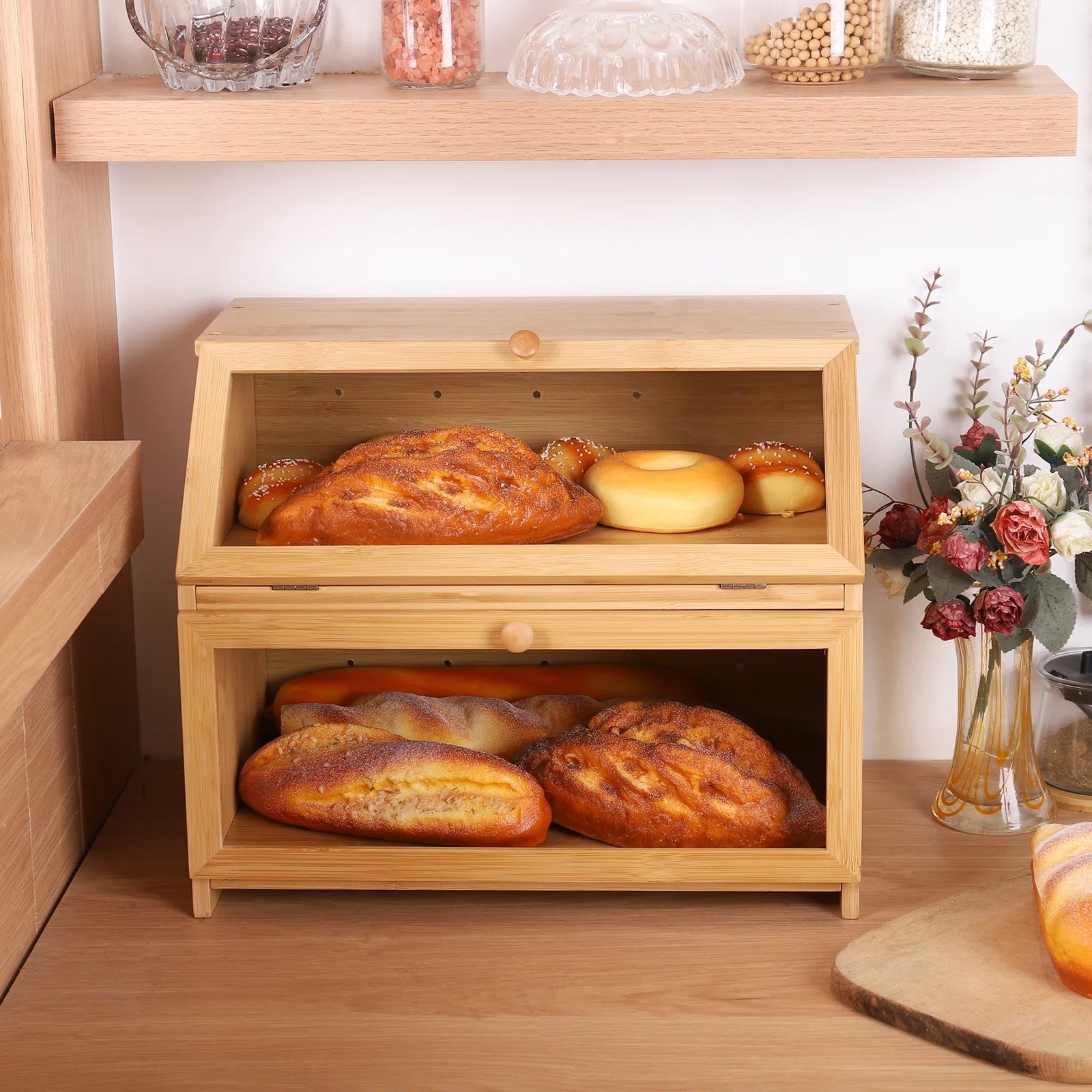 an oak bread box holding bread loafs and bagels