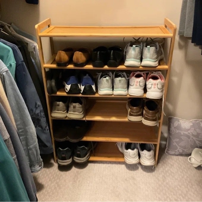 the wooden shoe rack holding different sneakers in a closest