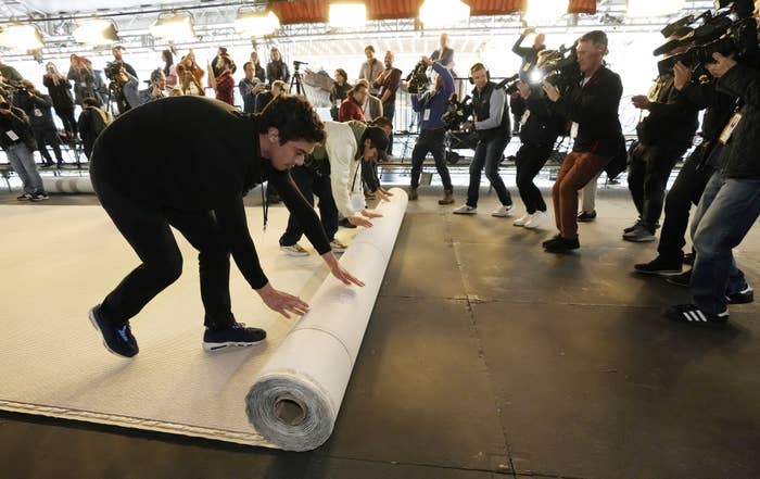 Photographers take photos of people rolling out the beige carpet