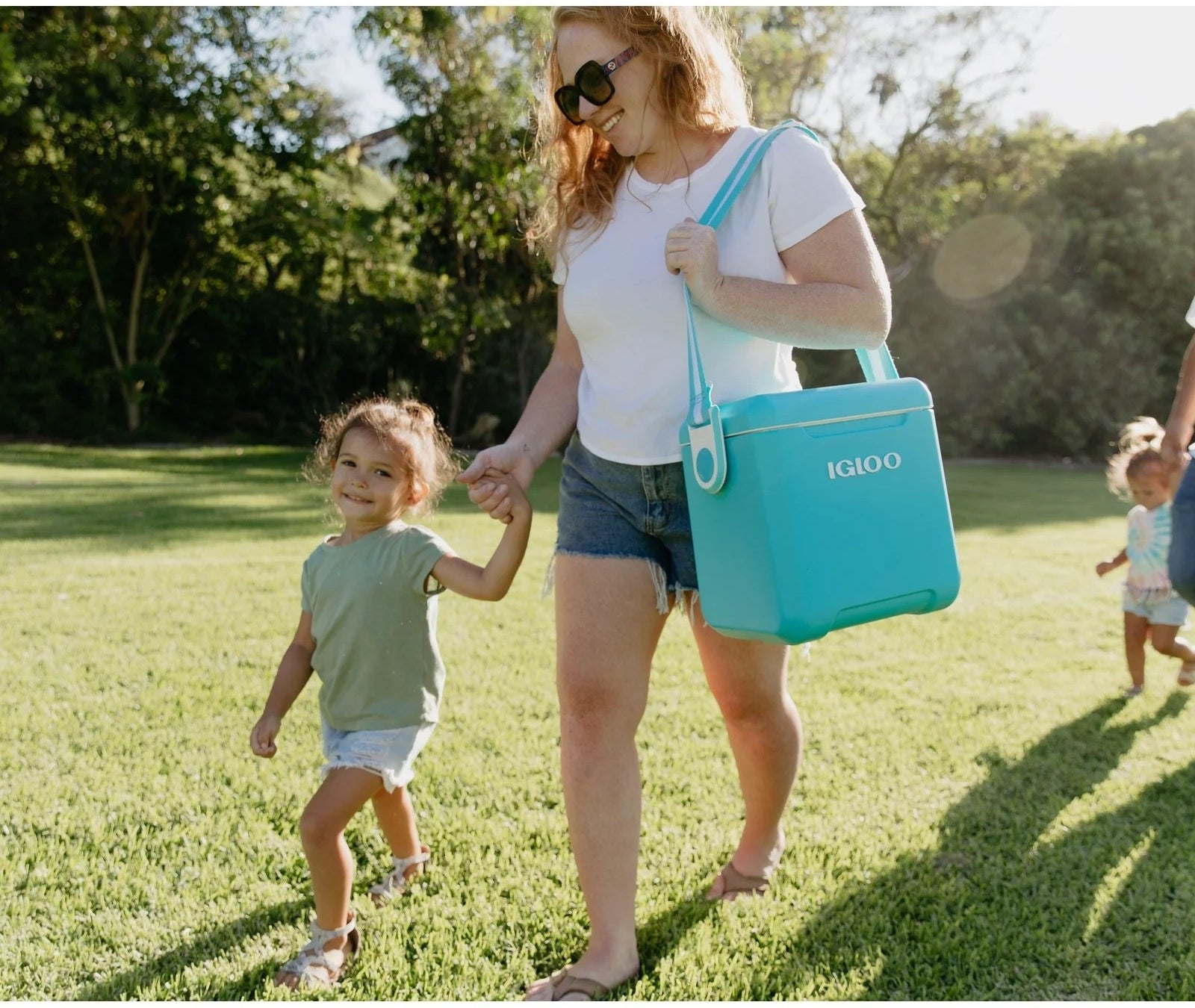model carrying a teal cooler with a shoulder strap