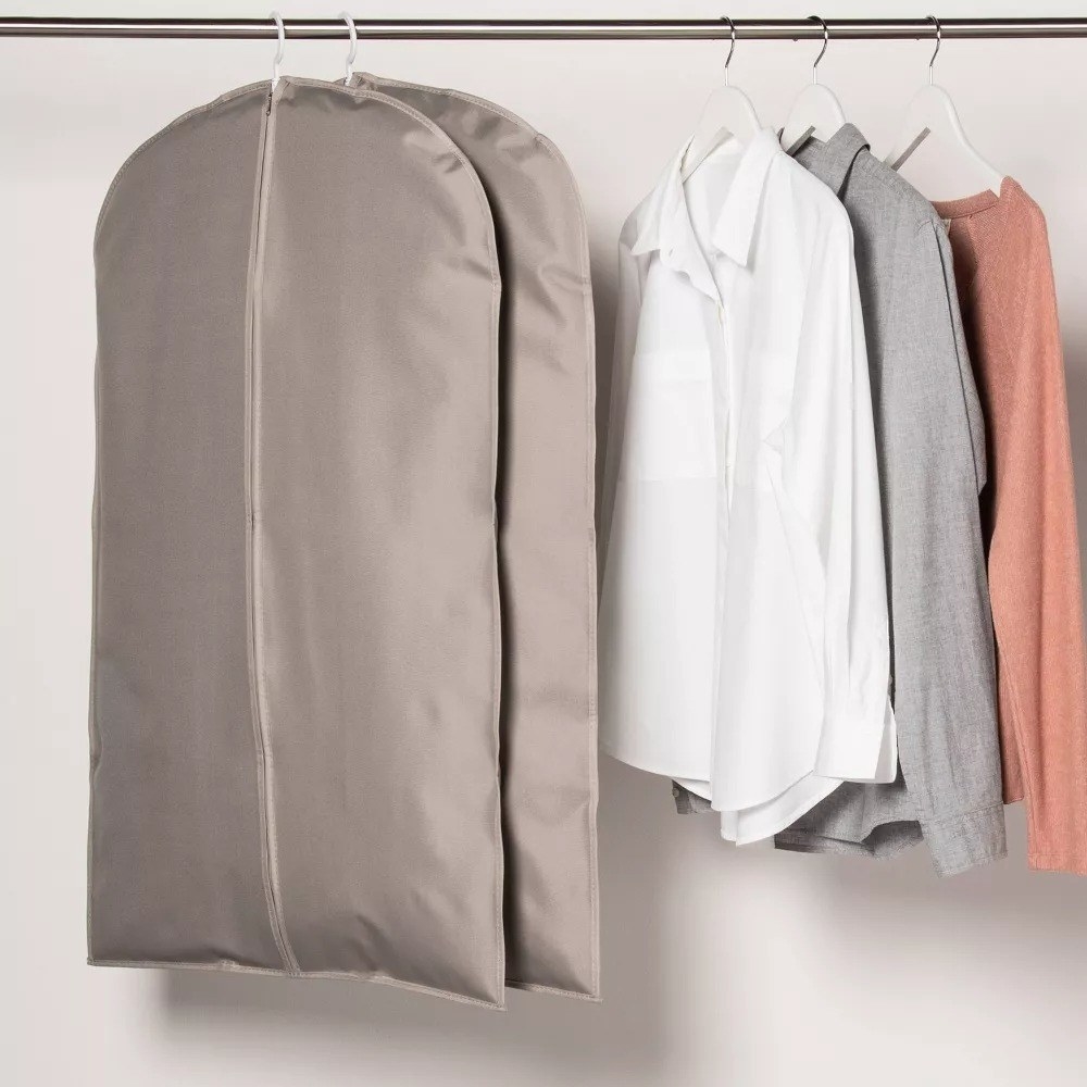 The two garment bags hanging next to a shirt and two sweaters