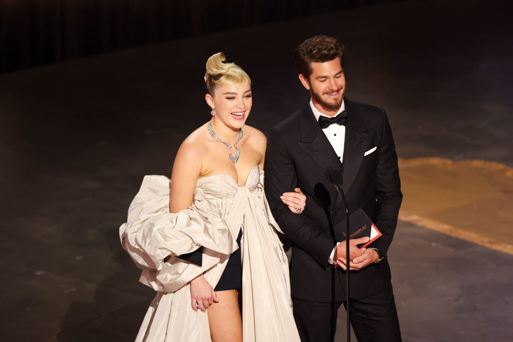 The two actors standing onstage presenting an award arm in arm