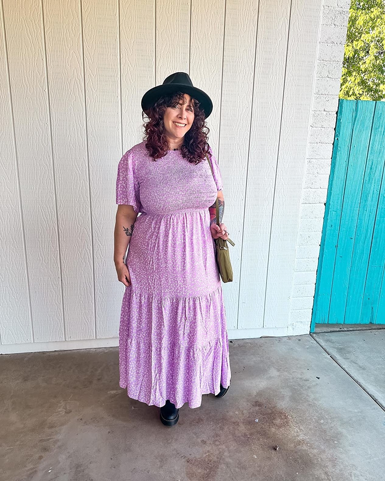 A reviewer wearing a purple dress with black accessories