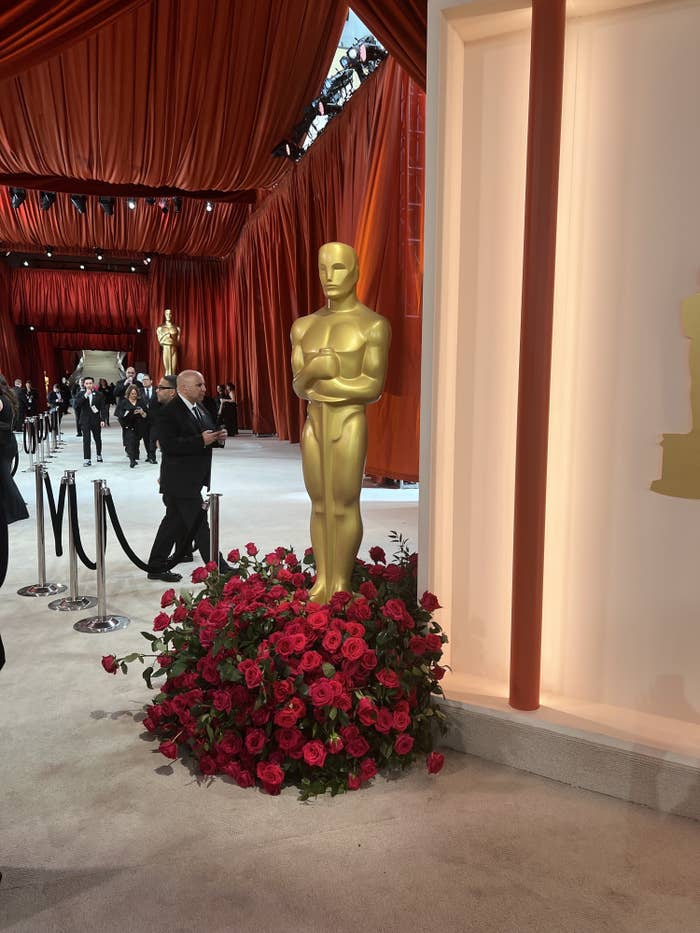 A closeup of an Oscar statue surrounded by roses on the the champagne carpet