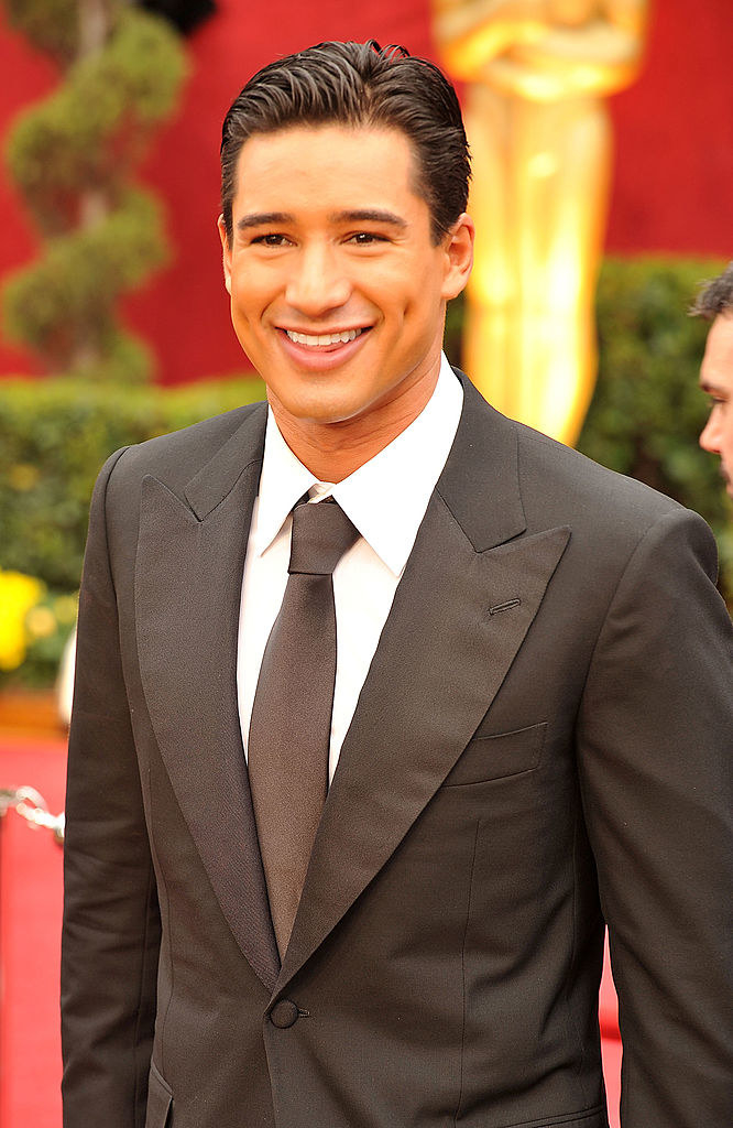 Mario smiling on the red carpet in a suit and tie