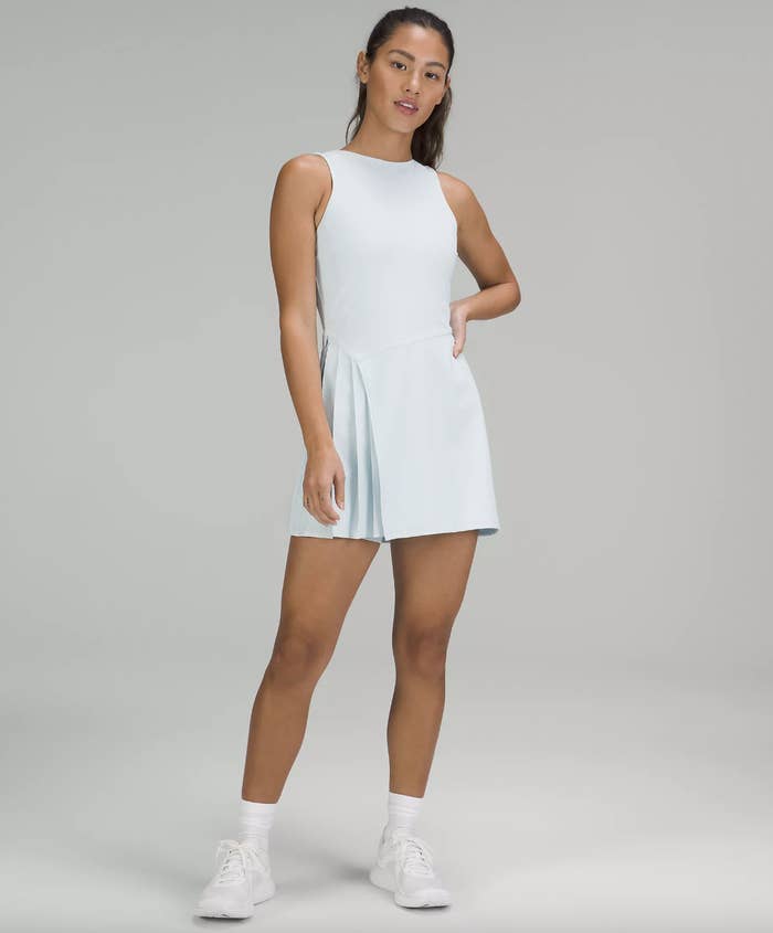 a person wearing the asymmetrical tennis dress with sneakers