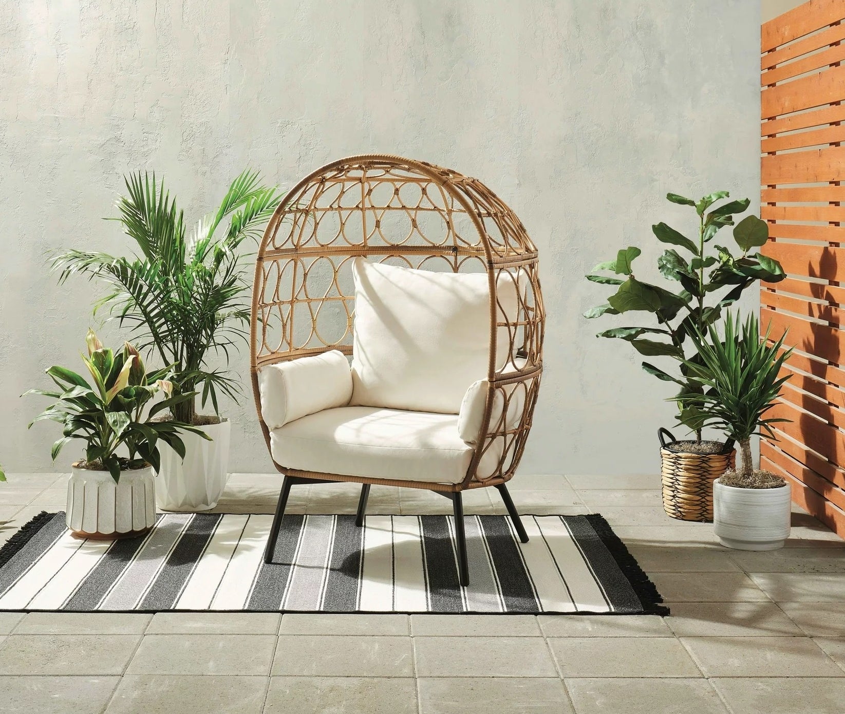 brown wicker egg chair with white cushions in a cute outdoor area