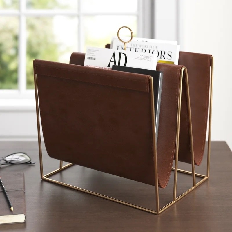 a faux leather and gold magazine holder on a wooden desk