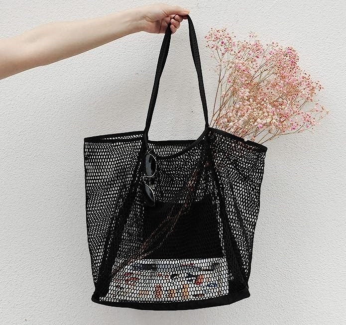 someone holding up a mesh tote with items visible inside