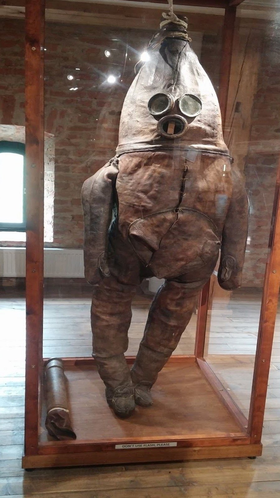 A statue in what looks like a misshapen skin suit with three glass circles for the face