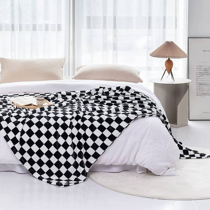 the throw blanket draped over the corner of a bed in a bedroom