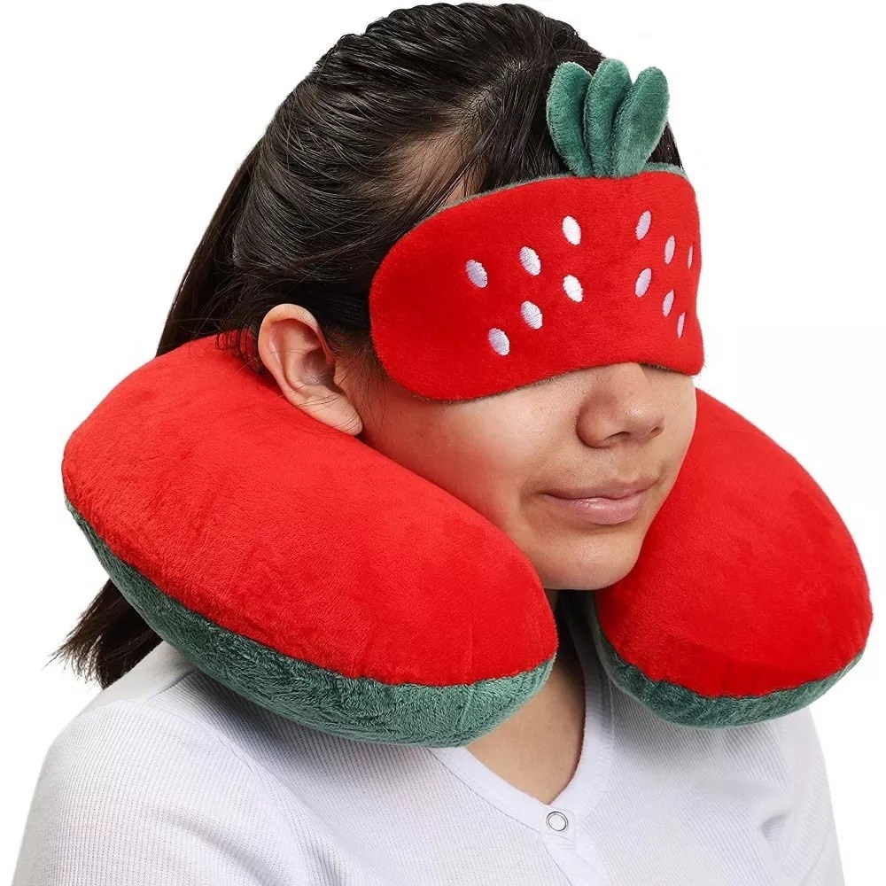 A model wearing the strawberry neck pillow and eye mask
