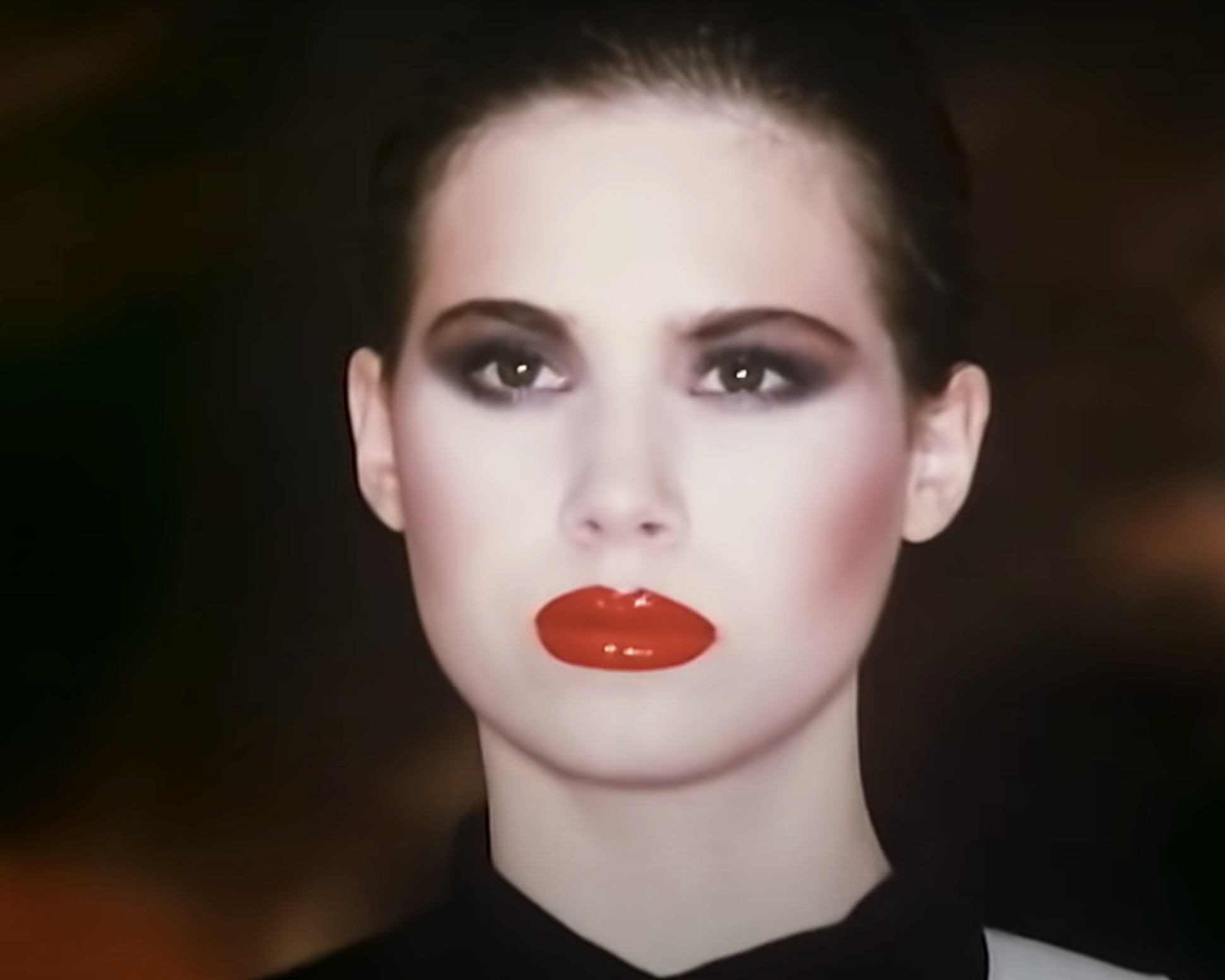 Close-up of woman with bright, shiny lips, dramatic eye makeup, and bright cheeks