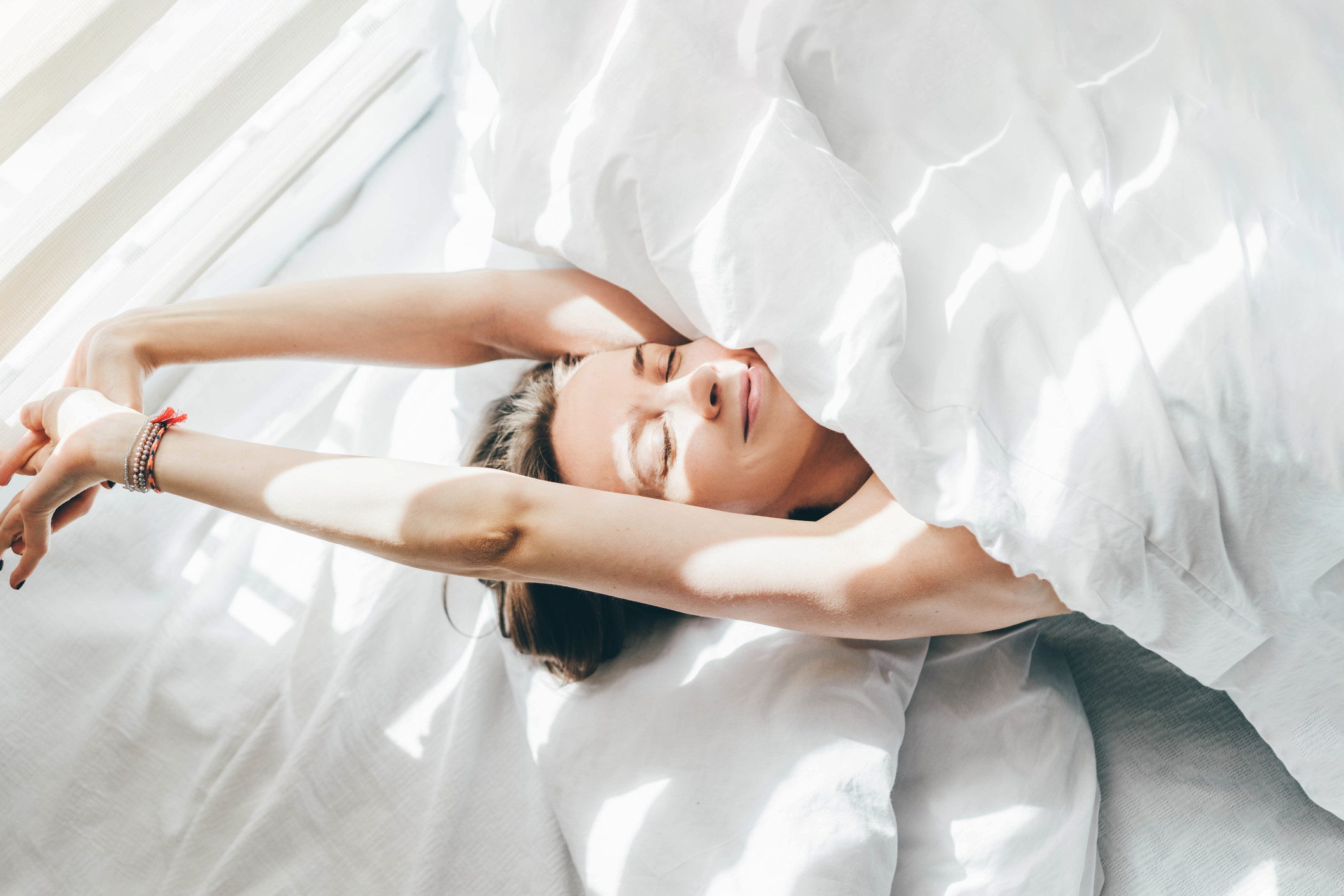 A woman stretching and smiling in bed