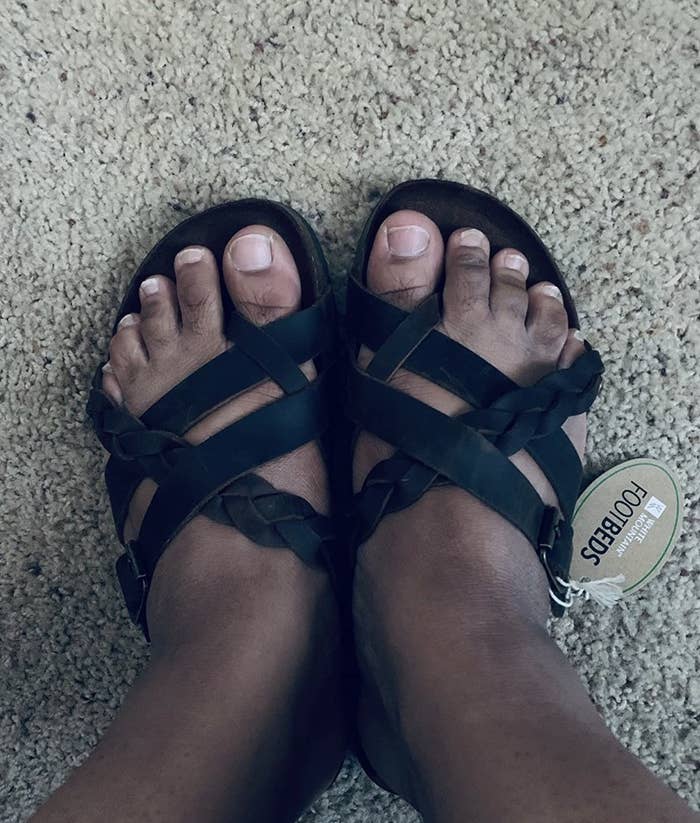 someone wearing a pair of black sandals with braiding detail