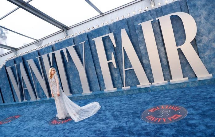 A person dressed in a gown poses for photographers on the Vanity Fair after party red carpet