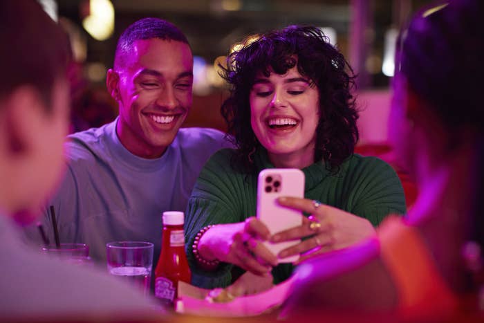 woman taking selfie with man on smart phone