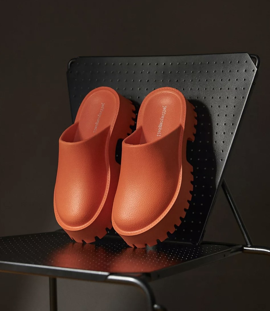 A pair of orange platform clogs on a black chair