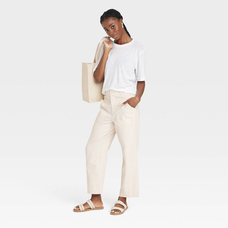 A model in the cream wide-leg utility pants