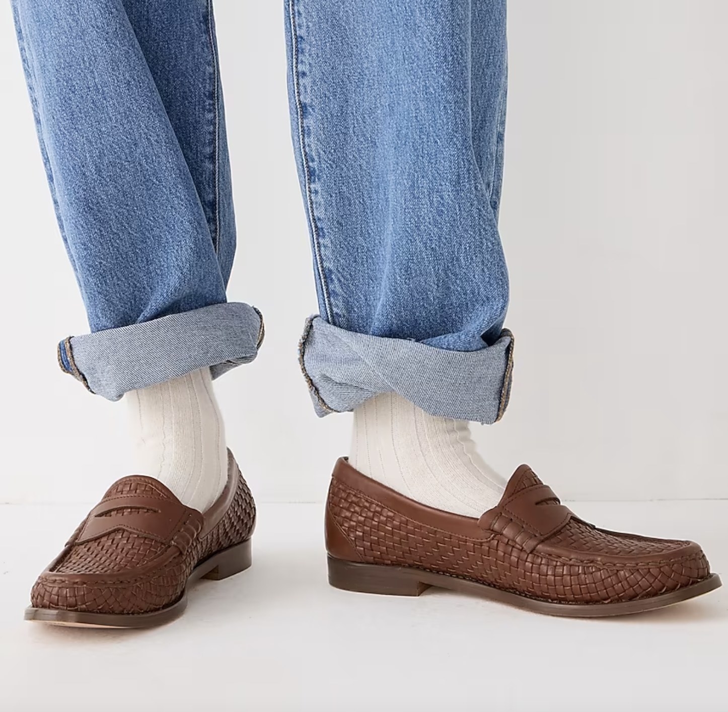 someone wearing jeans wearing brown penny loafers
